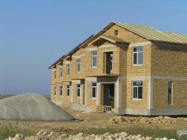 La foto - una casa con estructura de hormigón y paredes y frontones de piedra caliza.